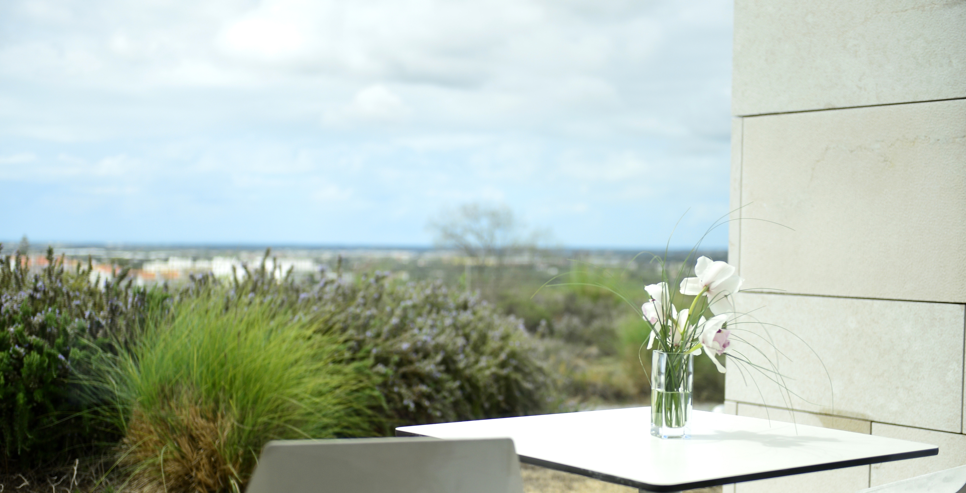 El Superior Premium View de la Pousada Palácio Estoi tiene una terraza con mesa, una jarra con flores y vista al jardín