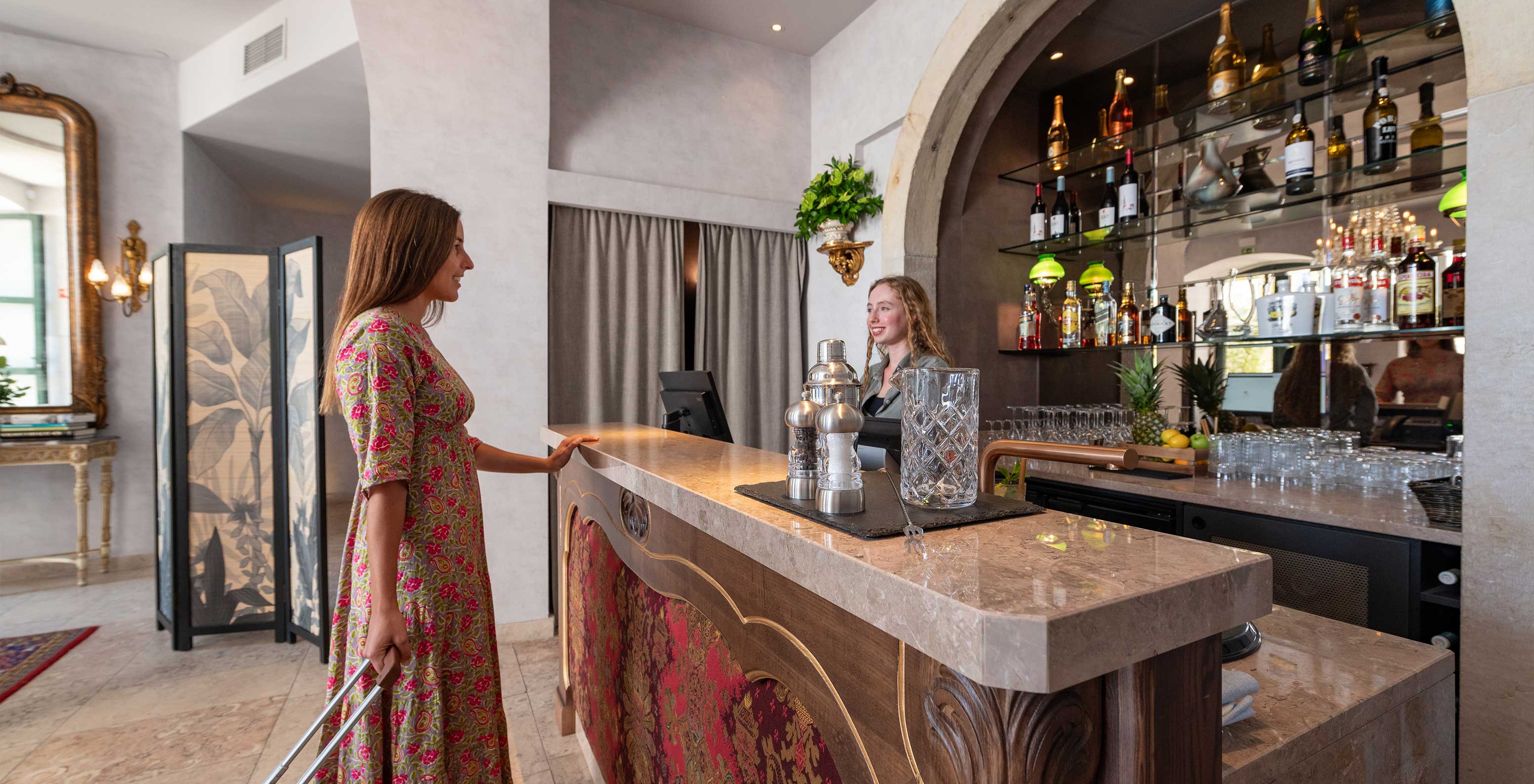 Cliente sonriente llegando al bar y recepción de la Pousada de Alfama en el centro histórico con una maleta