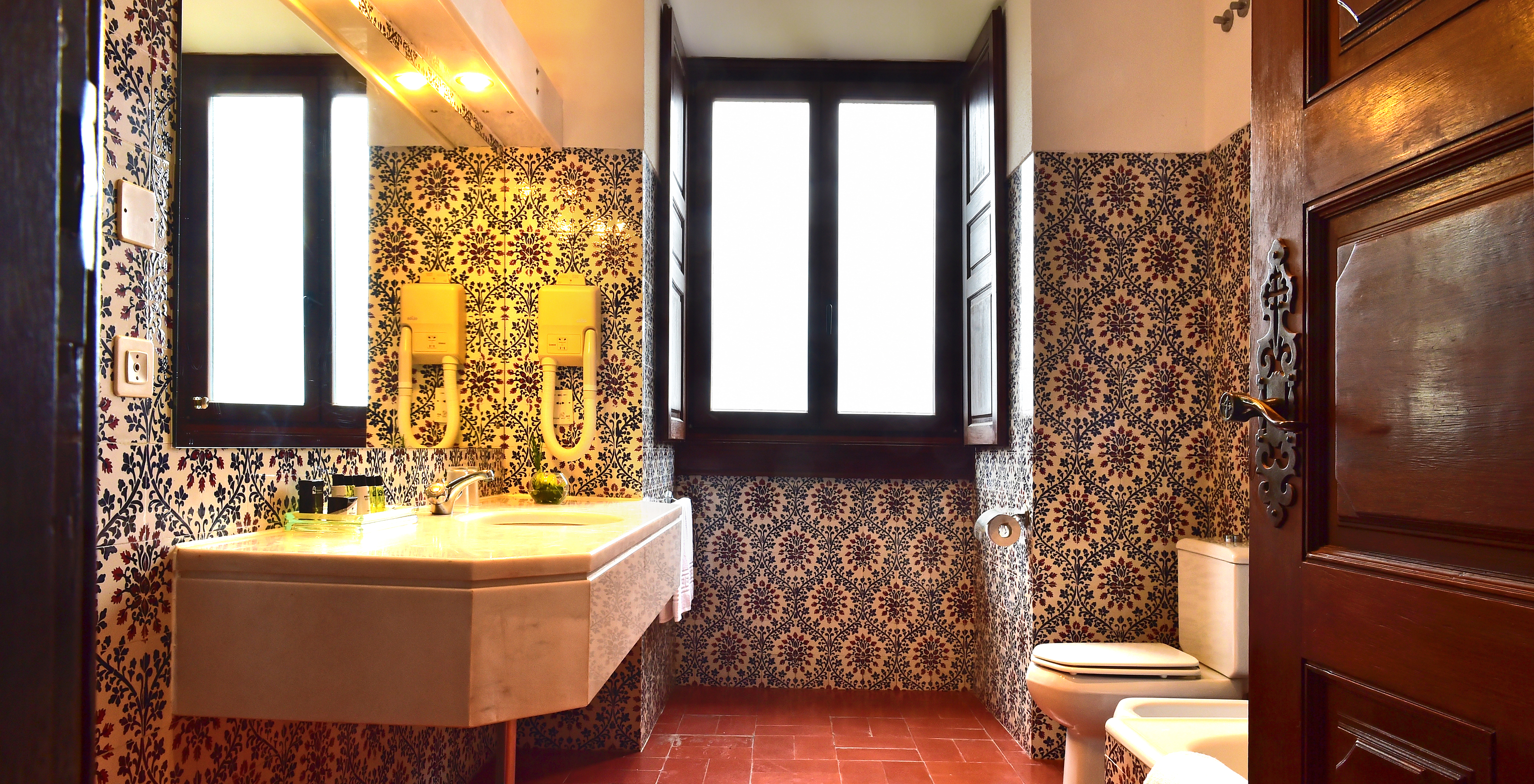 La Suite Standard de la Pousada Castelo Palmela tiene un baño con azulejos en la pared, una ventana y lavabo con espejo