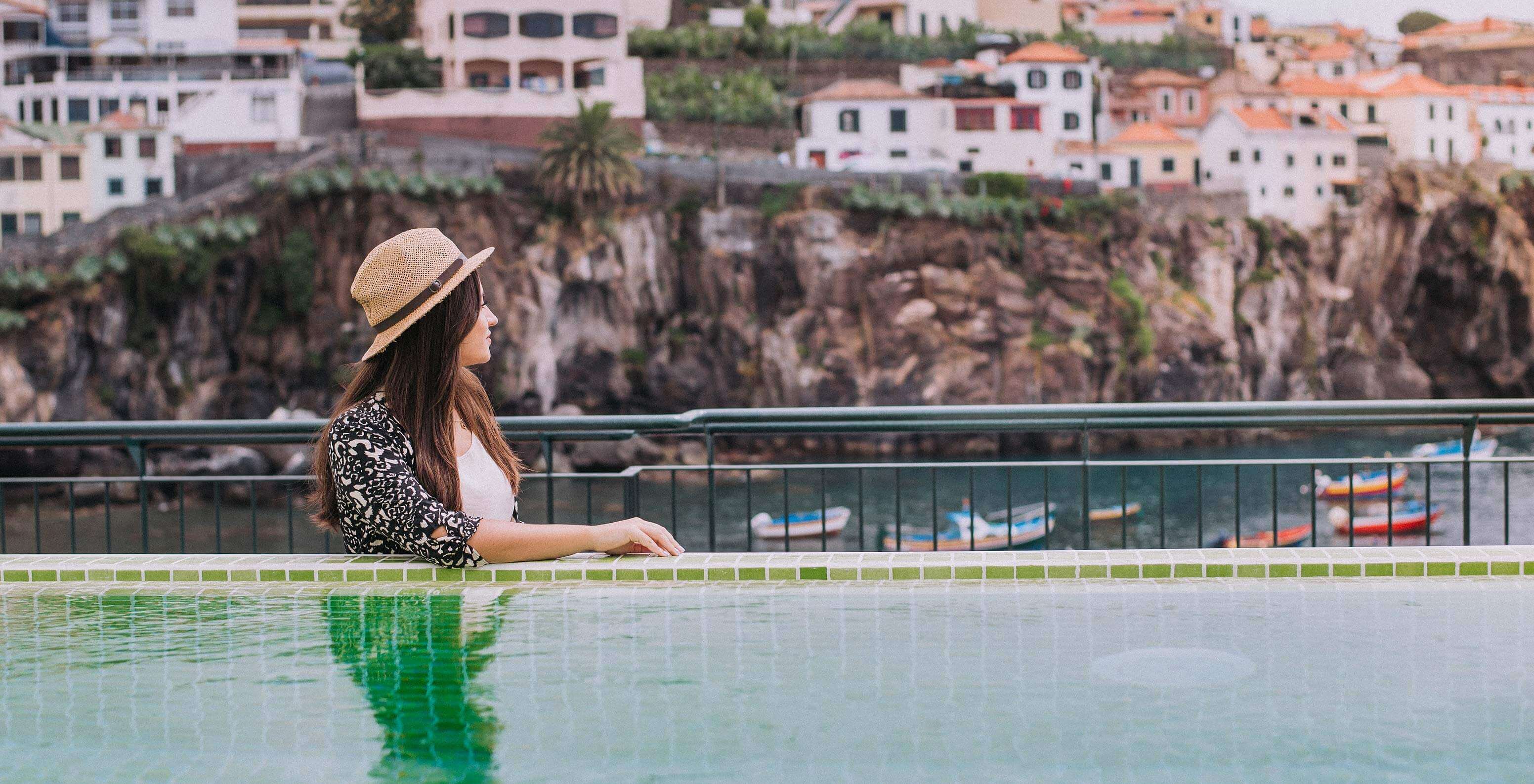 Chica disfruta de la vista de la Bahía de Câmara de Lobos desde la piscina exterior del Pestana Churchill Bay