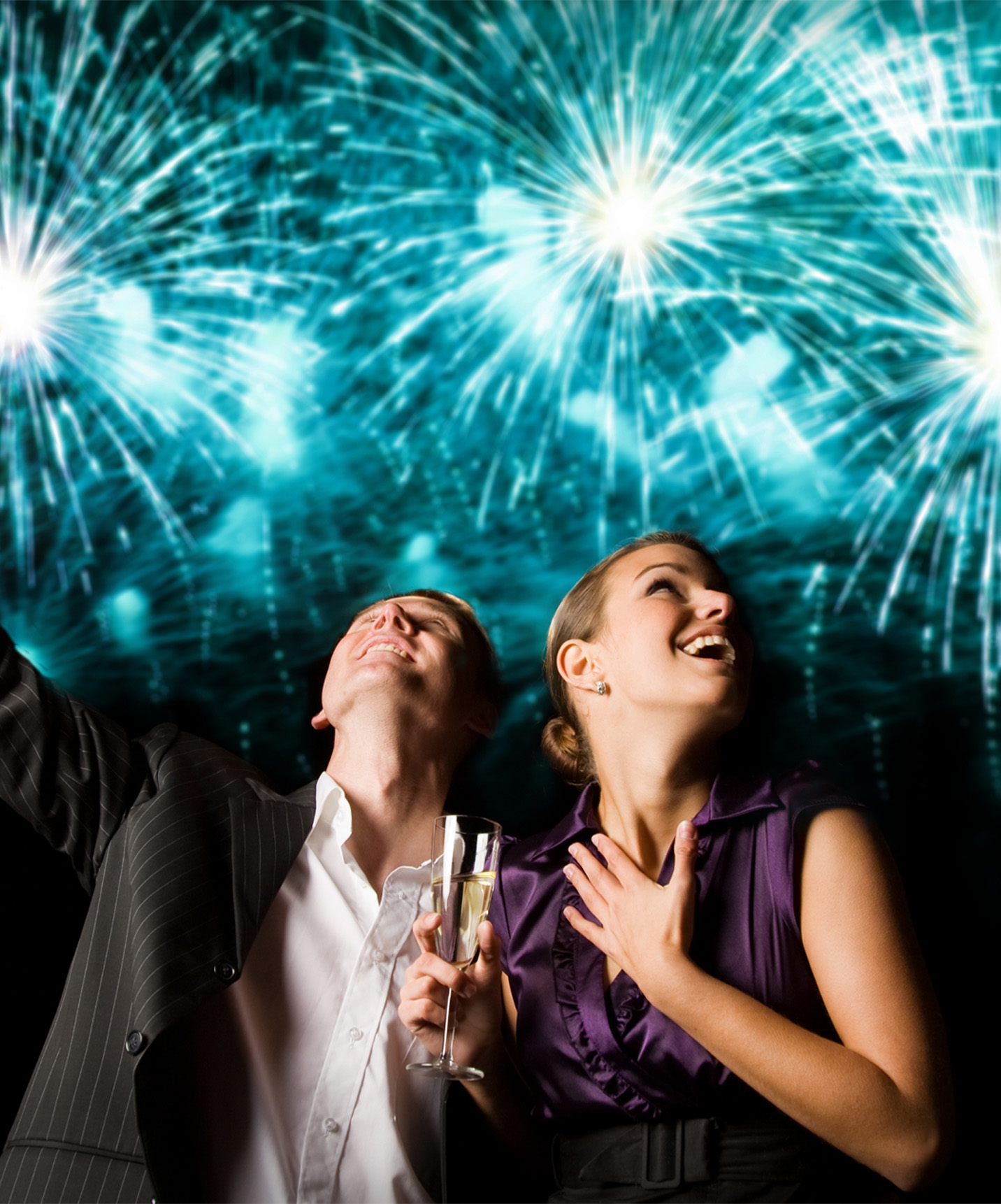 Pareja celebrando el Año Nuevo, con fuegos artificiales azules detrás, en una fiesta en un hotel del Pestana Hotel Group