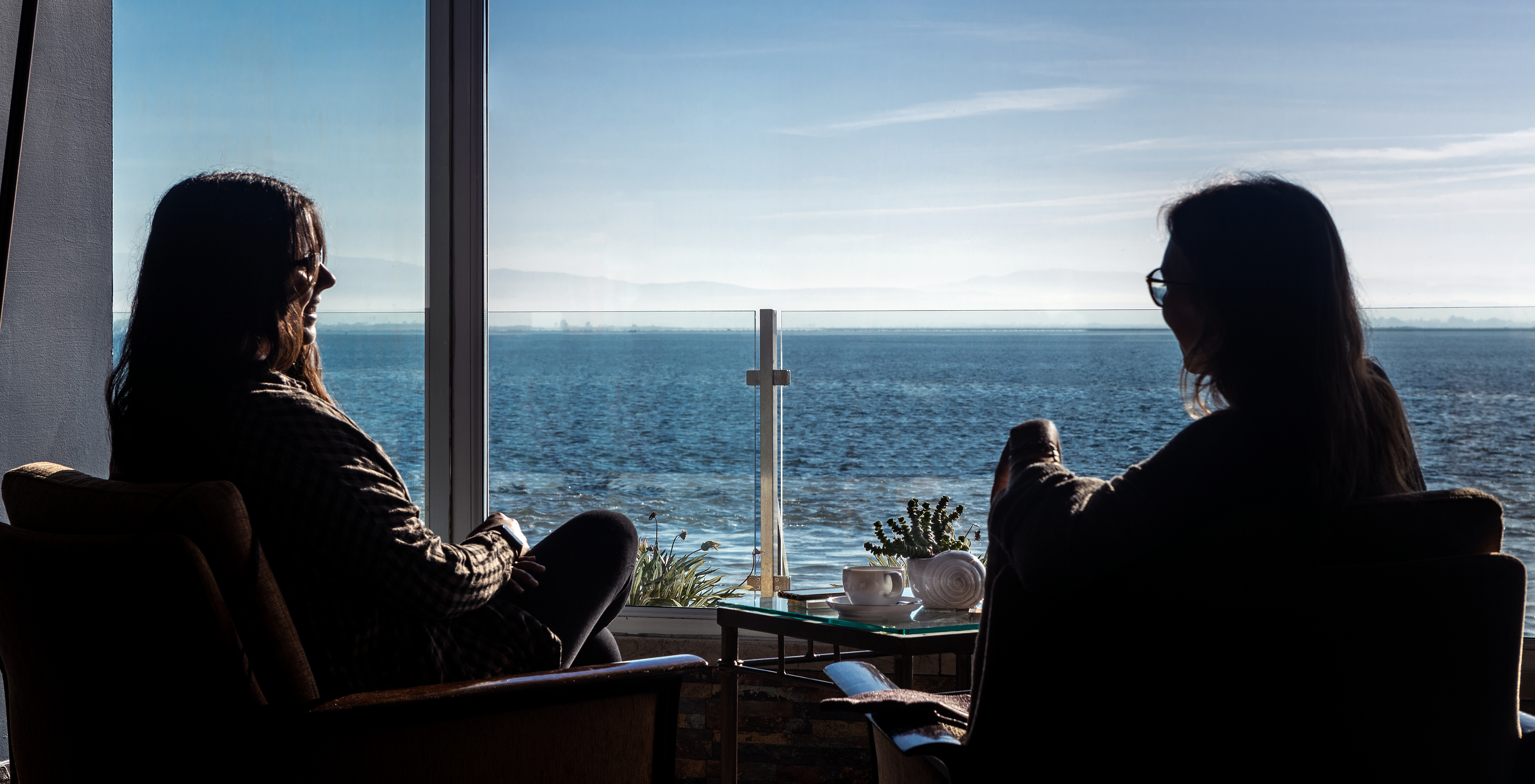 Dos personas sentadas con una mesa en el centro disfrutando de la vista de la ría de Aveiro