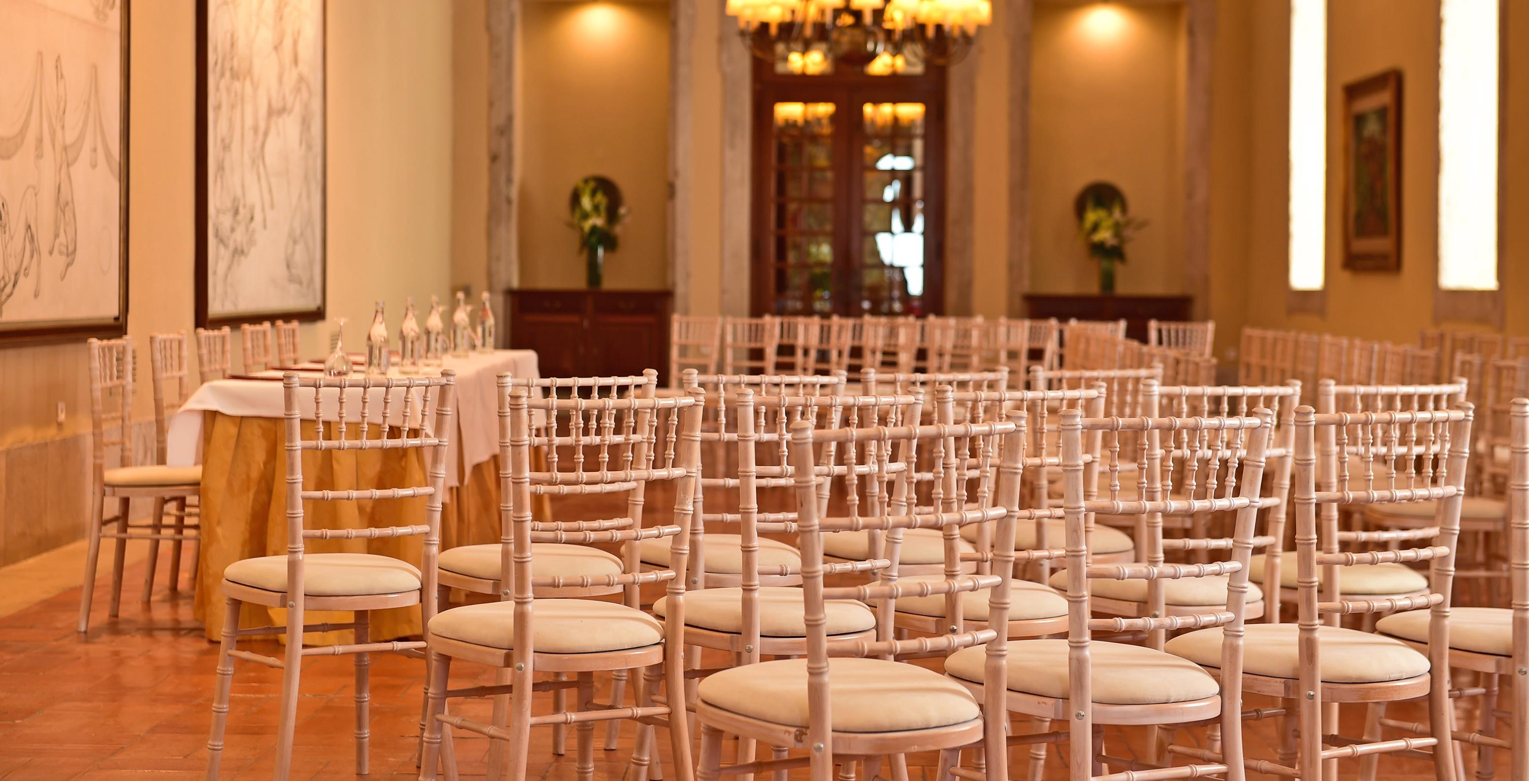 Sala de conferencias de Pousada Castelo Palmela, con varias sillas, cuadros y candelabros dorados