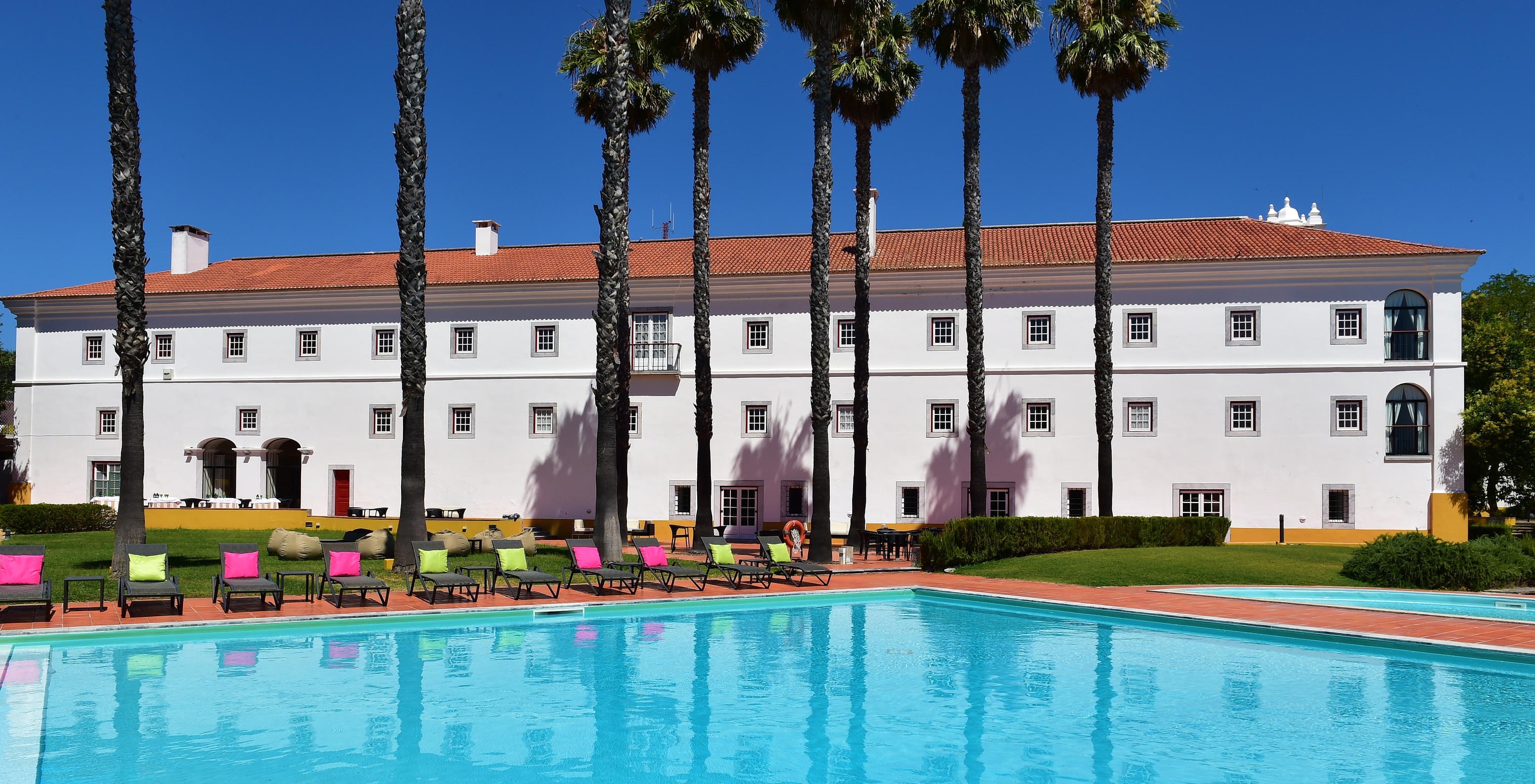 Outdoor pool of Pousada Convento Beja, a historic hotel in Alentejo, with several sun loungers with cushions