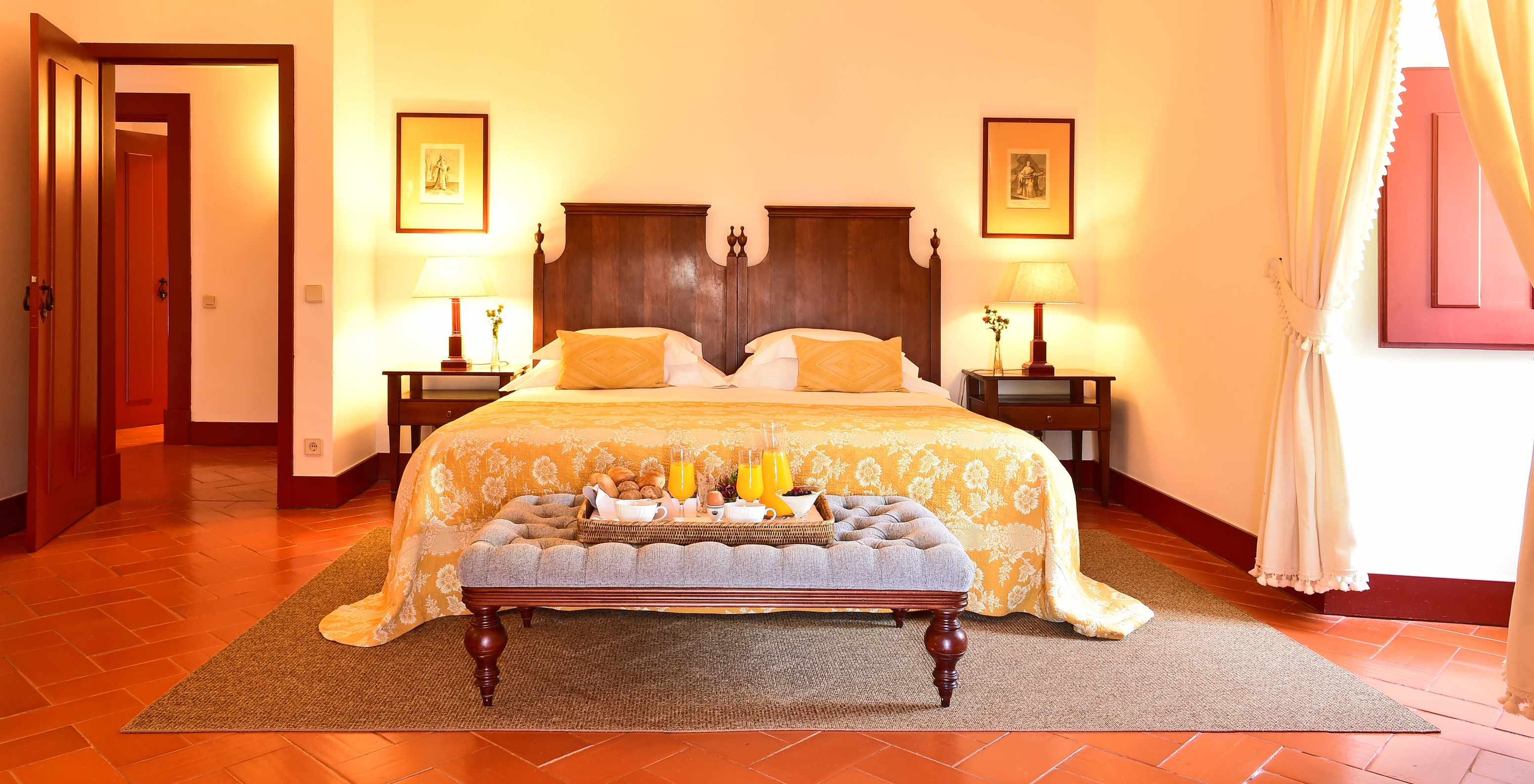 The Special Suite of The Pousada Convento Beja has a double bed with a yellow bedspread and a tray with breakfast