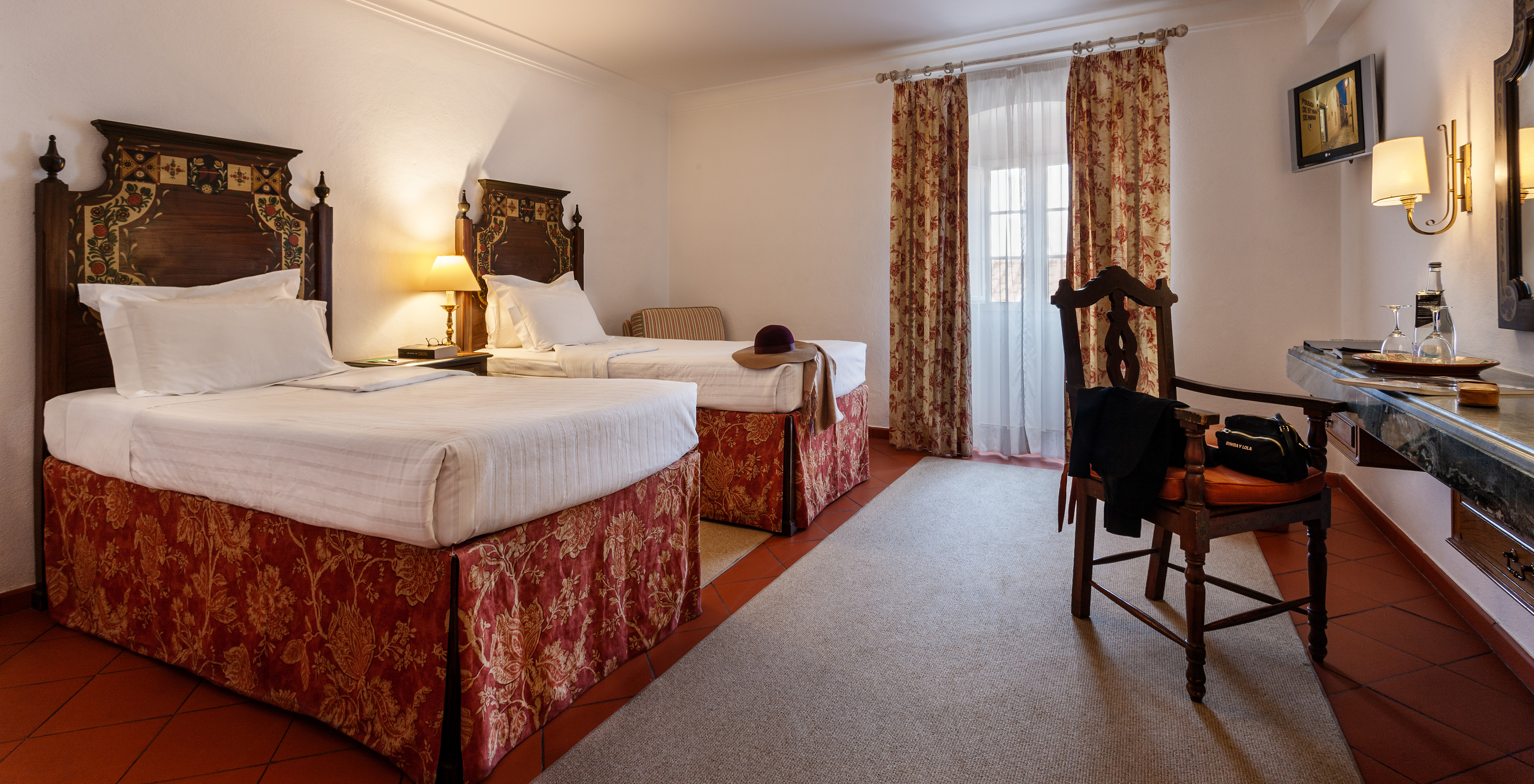 Le Chambre Familiale avec Balcon de la Pousada Marvão dispose de deux lits séparés à motif floral et d'un balcon