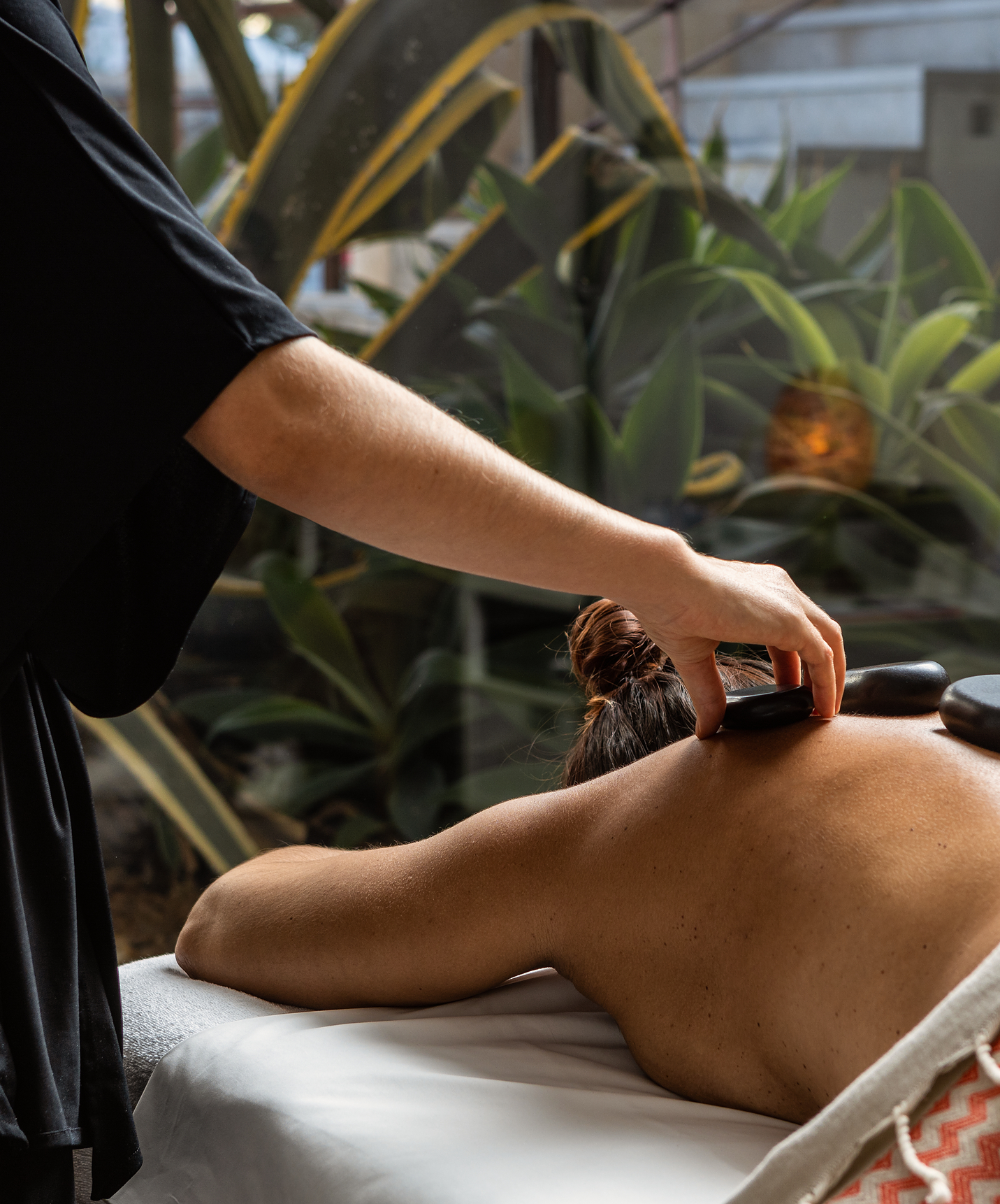 Femme reçoit un massage avec des pierres chaudes noires à la Pousada Convento Tavira, hôtel à Tavira avec piscine