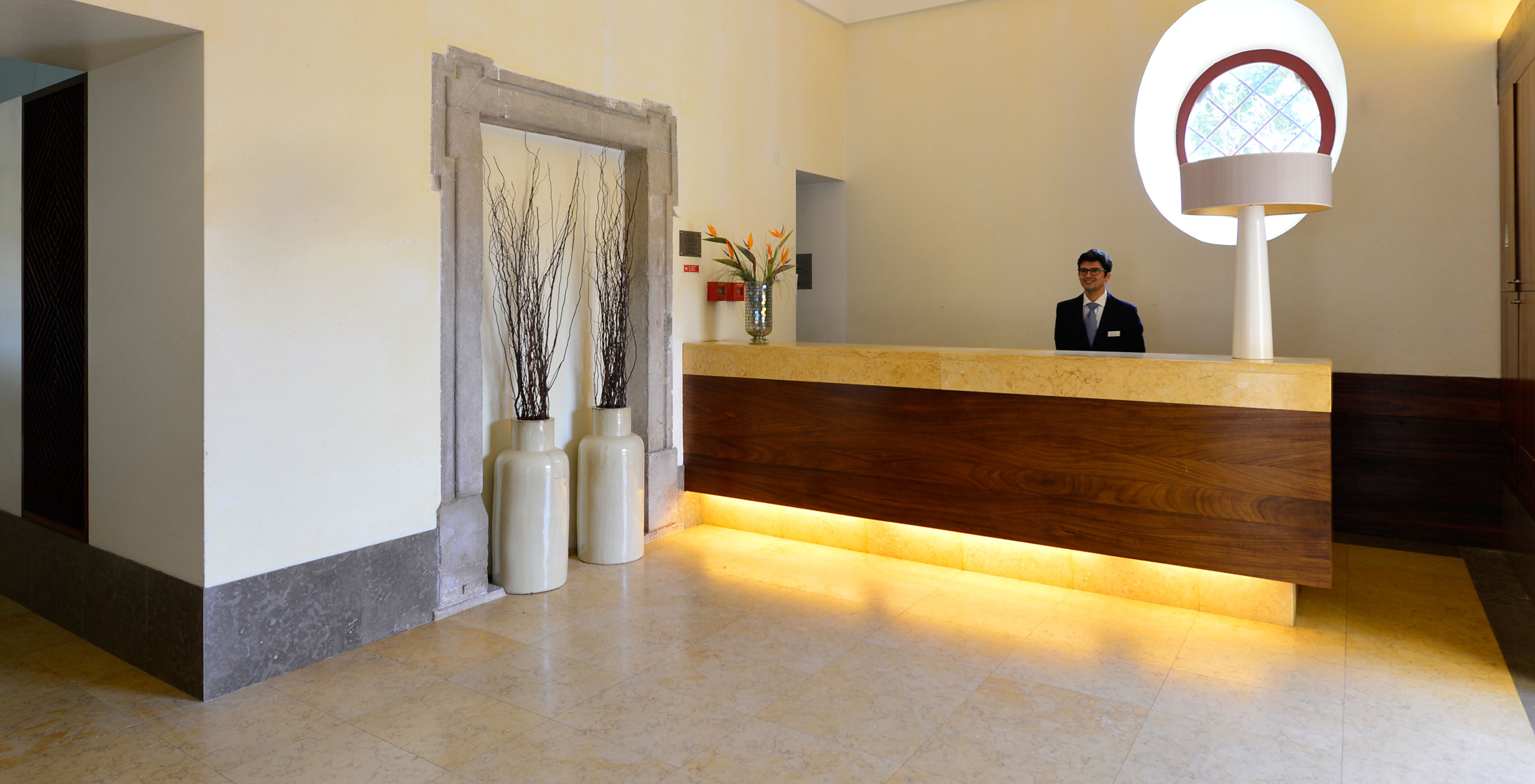 Réception avec un membre du personnel souriant prêt à servir les clients à la Pousada Convento Tavira