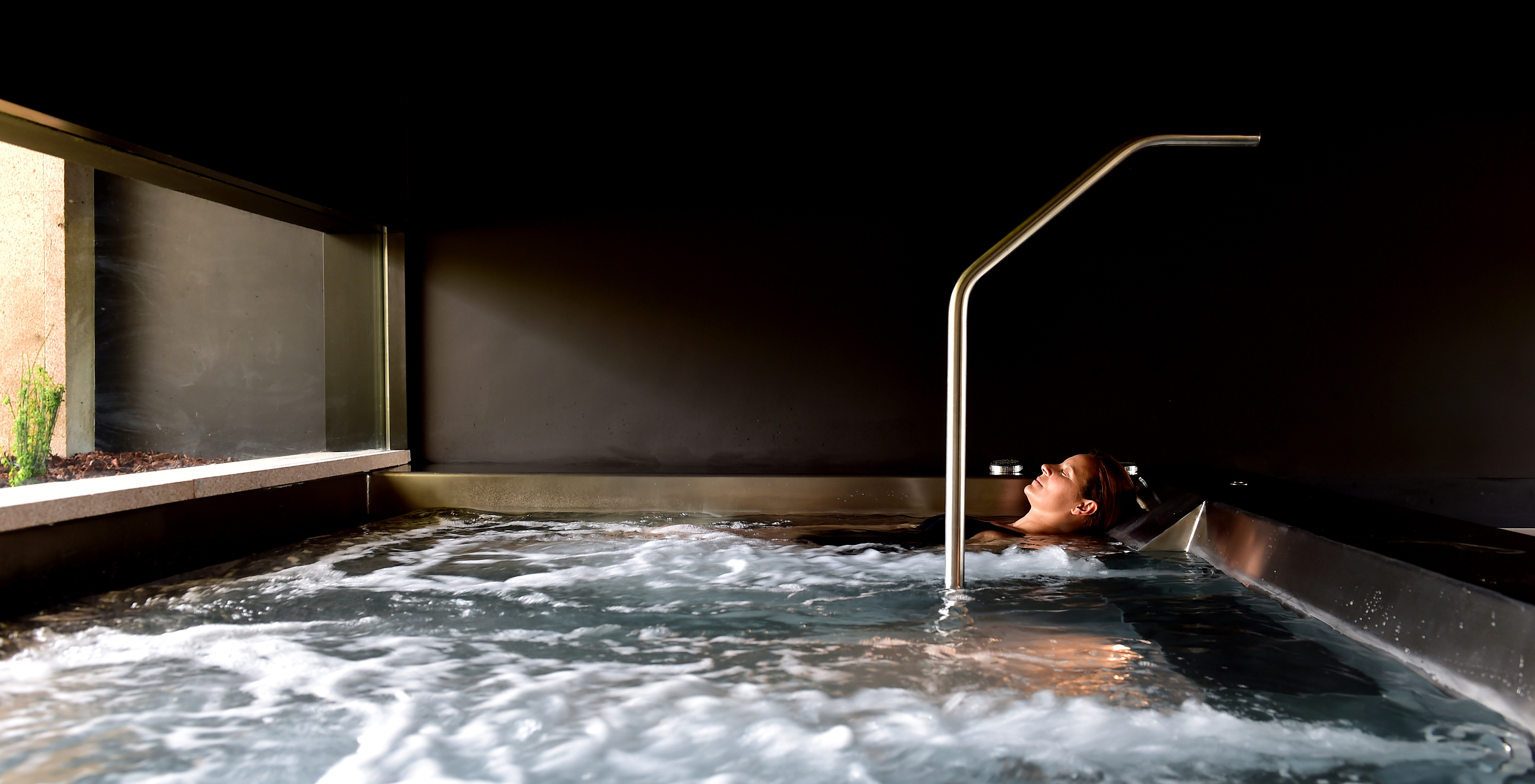 Jacuzzi van de Pousada Mosteiro do Crato met donkere muren en een groot raam voor natuurlijk licht