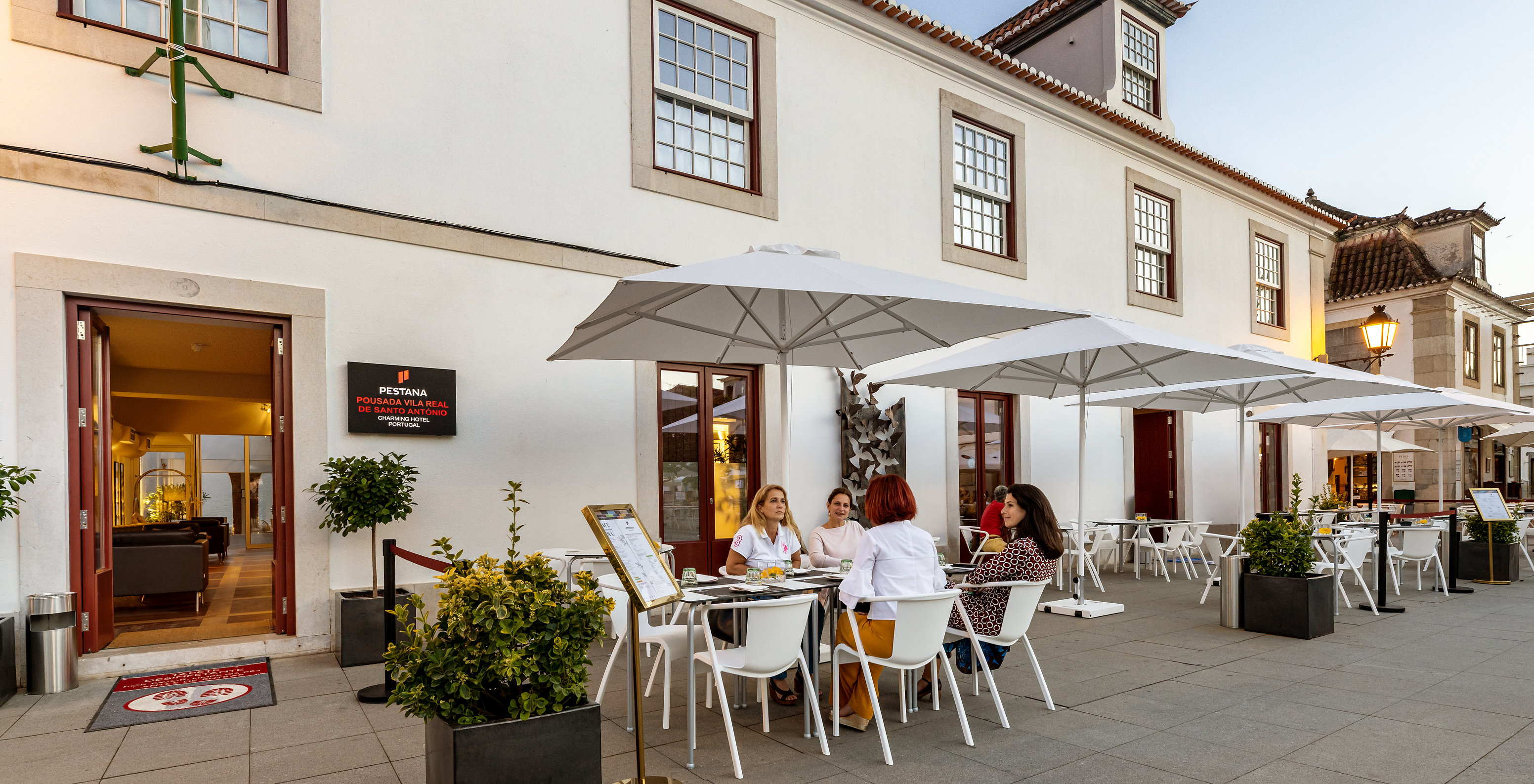 Ingang van Pousada Vila Real de Santo António met mensen op het terras van het restaurant die genieten van een maaltijd