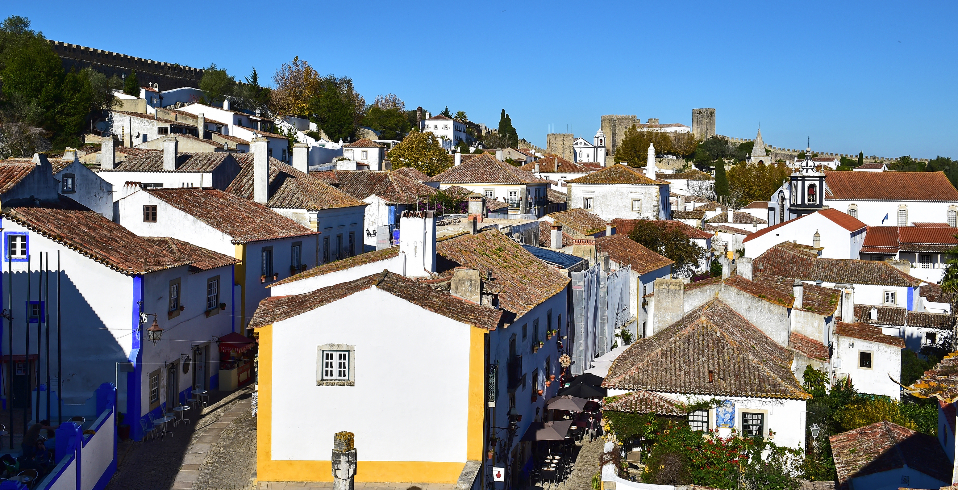 Uitzicht op Pousada Vila Óbidos Bed and Breakfast in Óbidos met verschillende gekleurde huizen en het kasteel van Óbidos