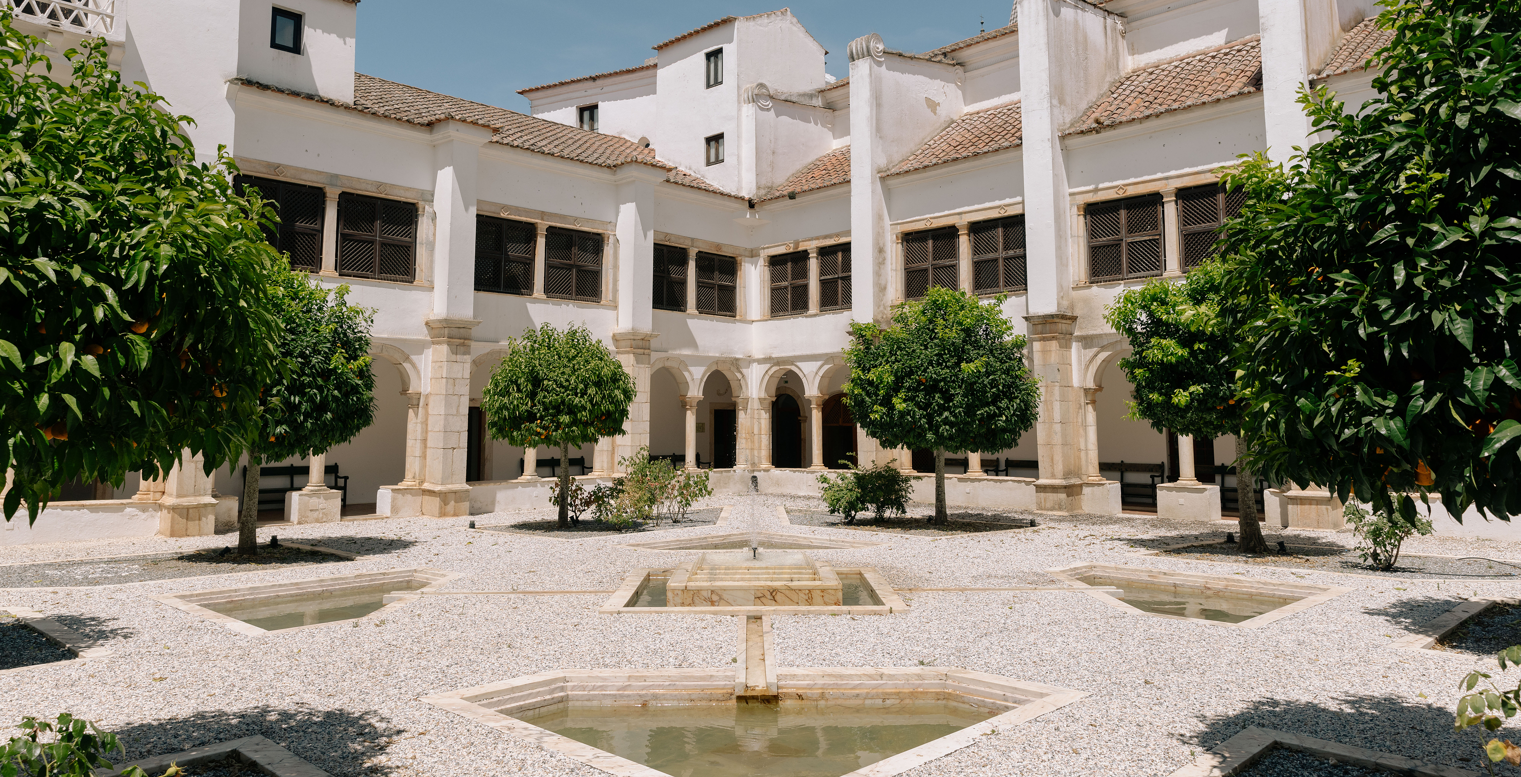 Pátio interior da Pousada Convento Vila Viçosa, no centro histórico, com várias laranjeiras e uma fonte no centro