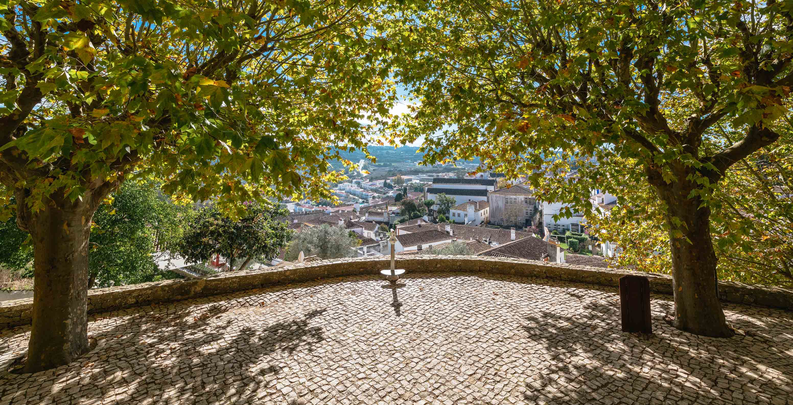 Miradouro no exterior da Pousada Castelo de Óbidos com sombra das árvores e vista sobre a cidade de Óbidos