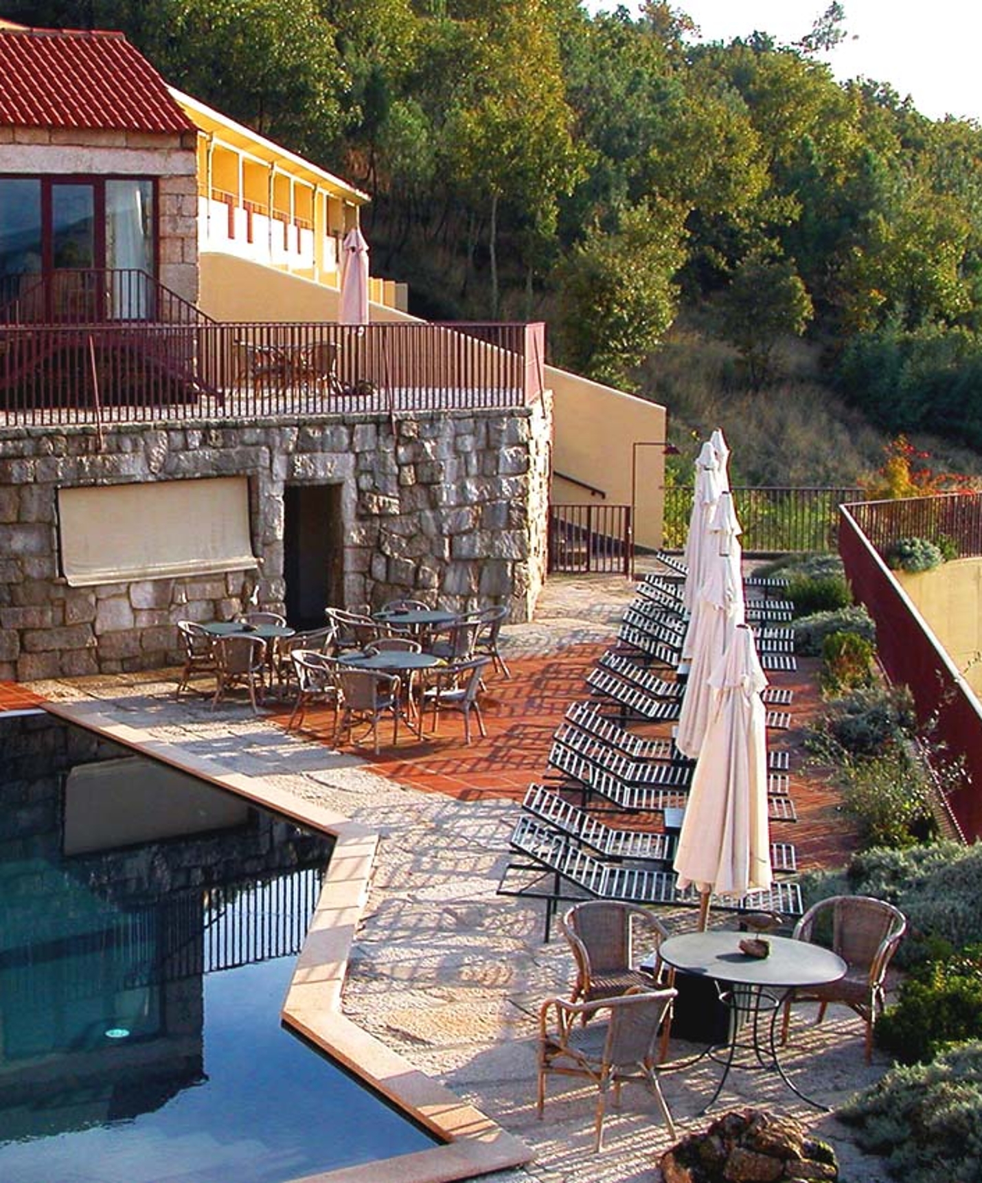 Hotel histórico em Belmonte com piscina exterior, numa varanda com espreguiçadeiras e chapéus de sol fechados