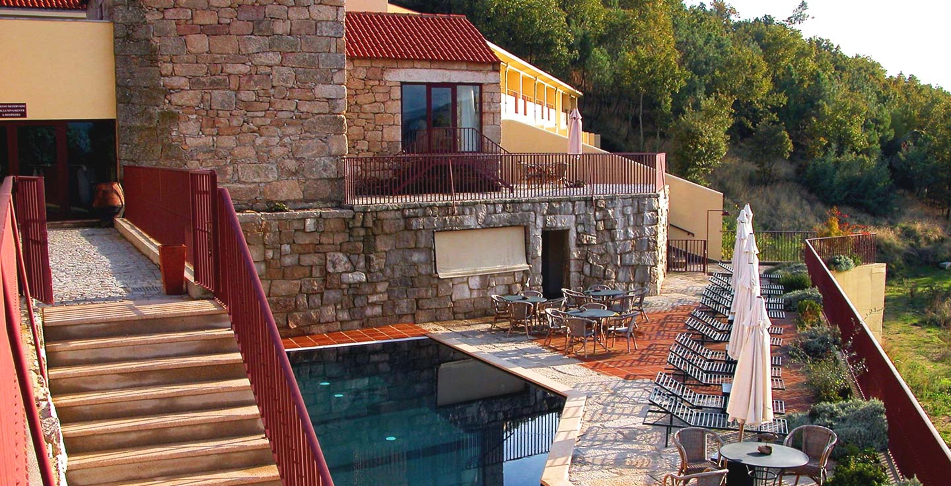 Hotel histórico em Belmonte com piscina exterior, numa varanda com espreguiçadeiras e chapéus de sol fechados