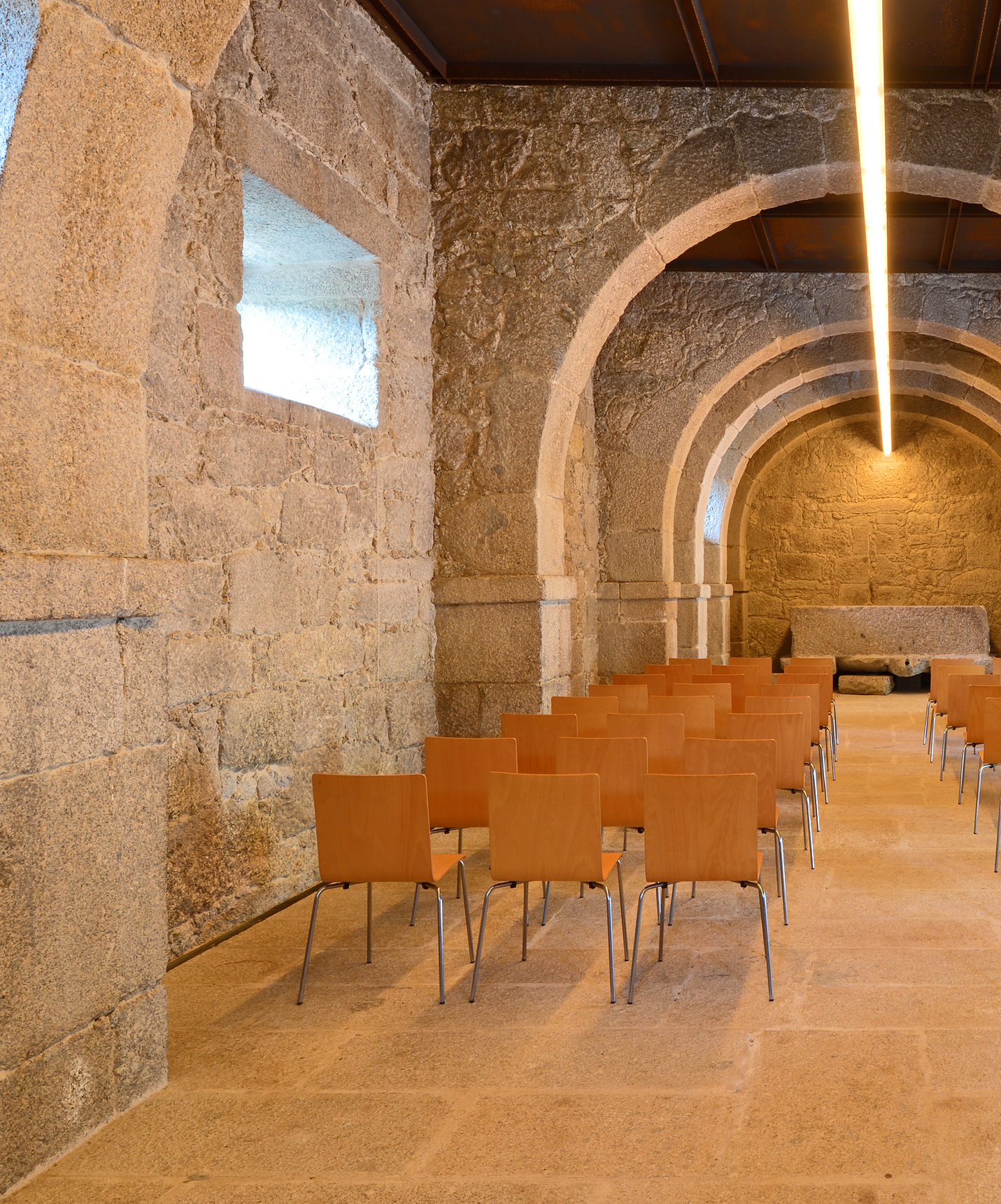 A Pousada Mosteiro Amares, um Hotel Histórico em Amares, tem uma sala de eventos com parede de pedra e várias cadeiras