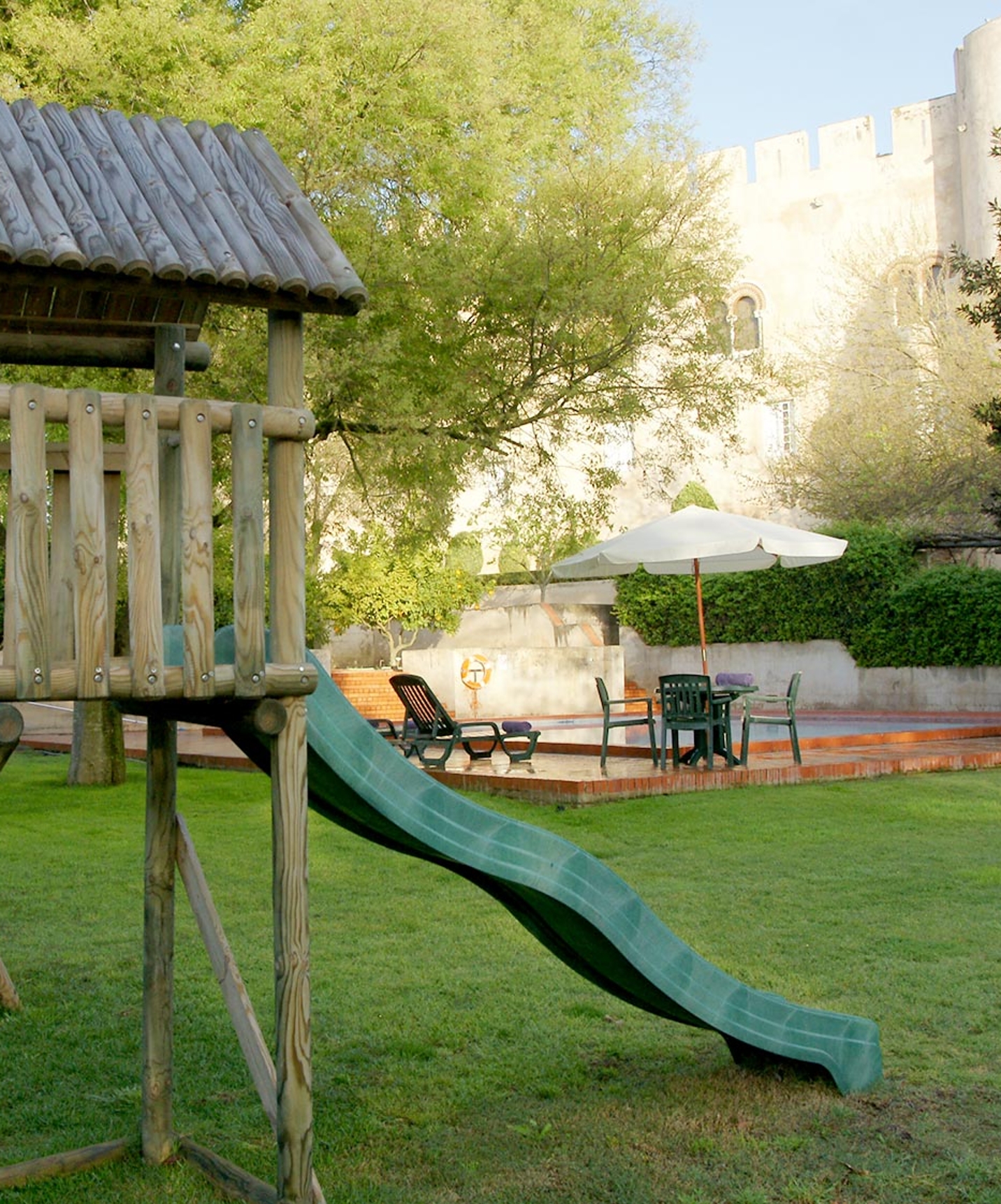 Jardins bem cuidados com piscina e escorrega para crianças na Pousada Castelo Alvito, Hotel em Alvito com Spa