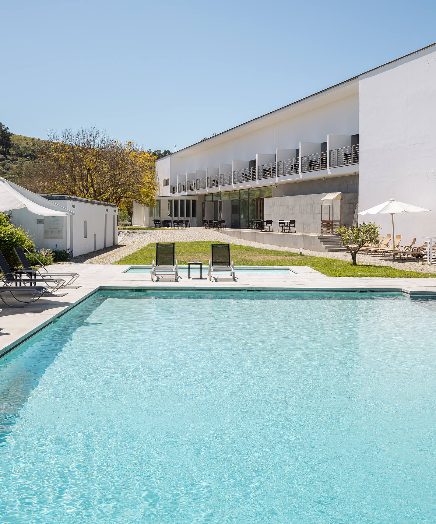 Piscina exterior da Pousada Convento Arraiolos com espreguiçadeiras e no meio da natureza