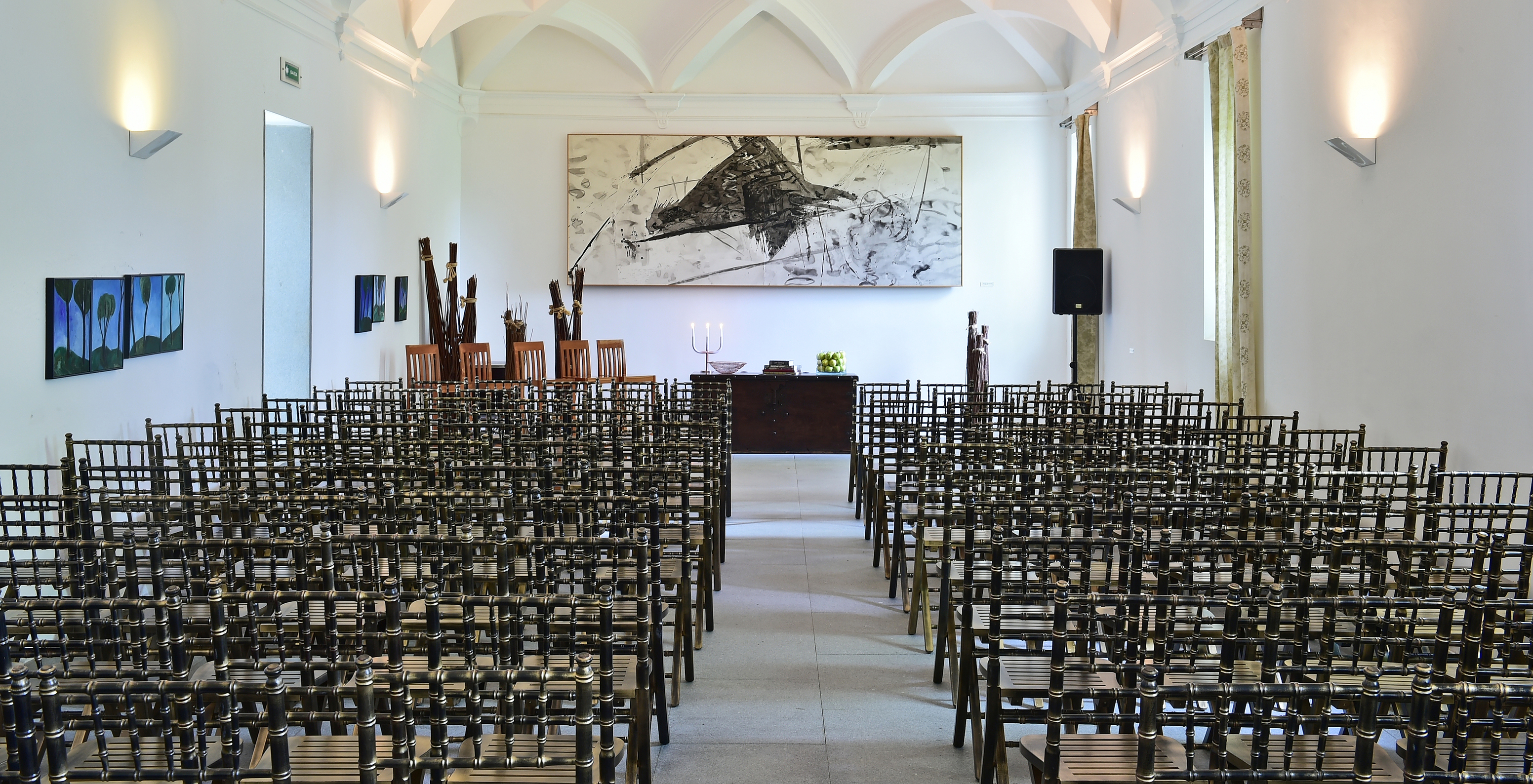 Sala de reuniões da Pousada Convento Arraiolos com uma mesa e várias cadeiras preparadas para uma plateia